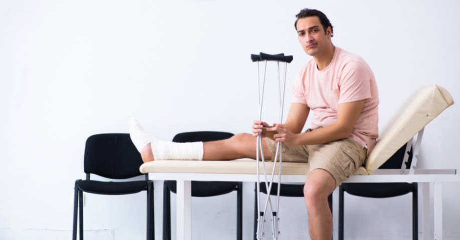 Joven con muletas esperando en la sala del hospital