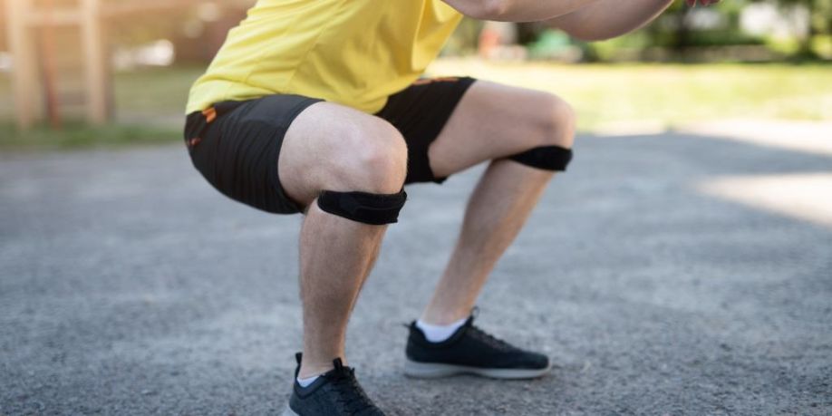 Hombre haciendo sentadillas en vendaje de soporte de rodilla